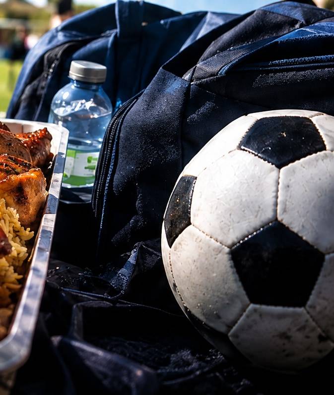 Pelota de fútbol, bolso deportivo y botella de agua junto a una bandeja de comida